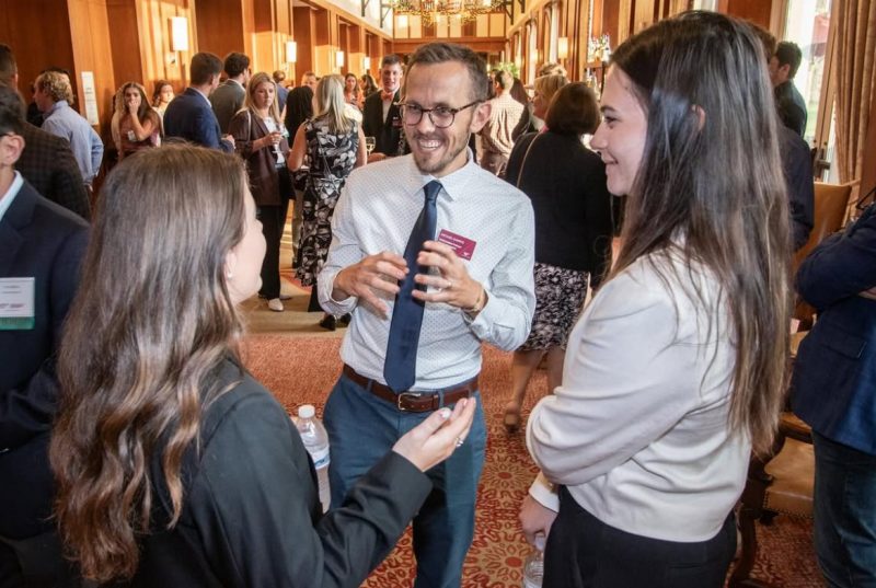 Faculty and students talking together at a professional event.