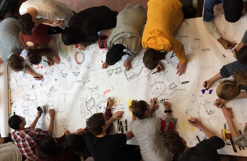 Students drawing on large piece of paper together